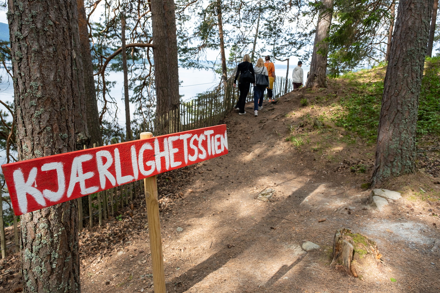 Elever går på en sti gjennom skogen. I forgrunnen et skilt der det står kjærlighetsstien.  